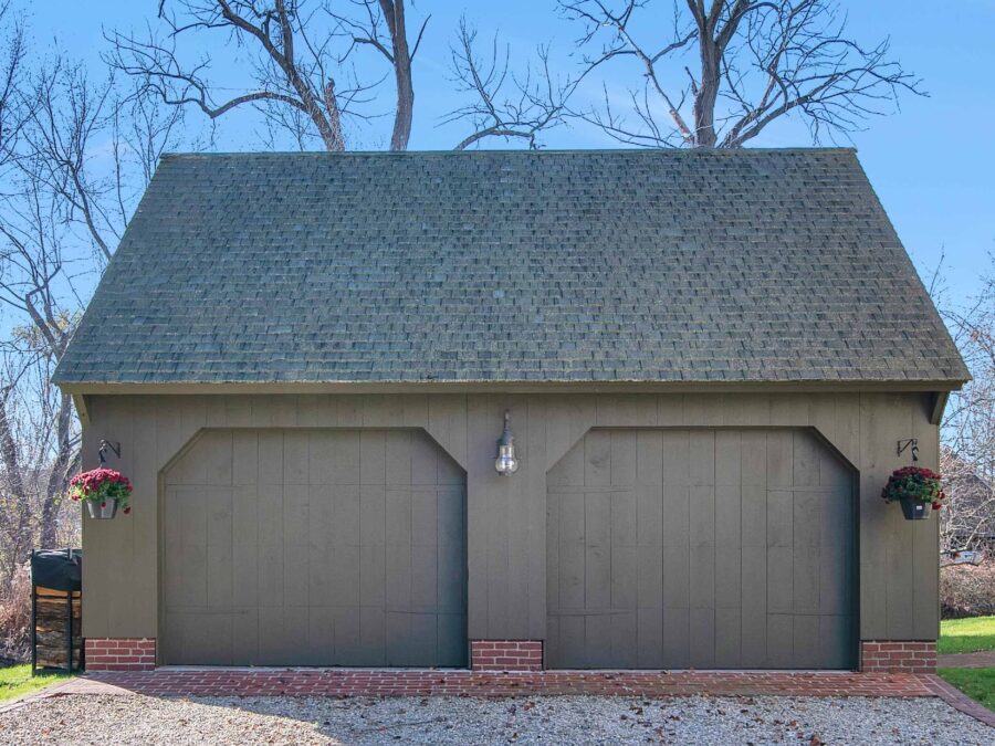 Green Carriage House with brick foundation and blue skies
