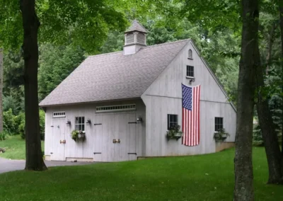 Gray barn with flower boxes and a big American flag hanging on the side